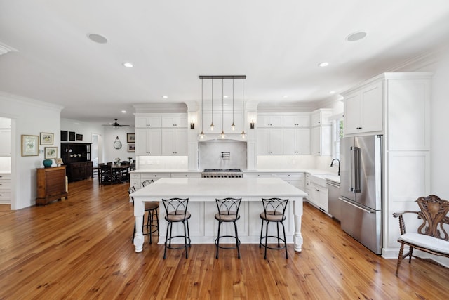 kitchen with light wood-type flooring, a kitchen island, stainless steel appliances, and light countertops