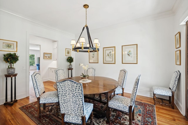 dining area featuring light wood-style flooring, ornamental molding, a chandelier, and baseboards