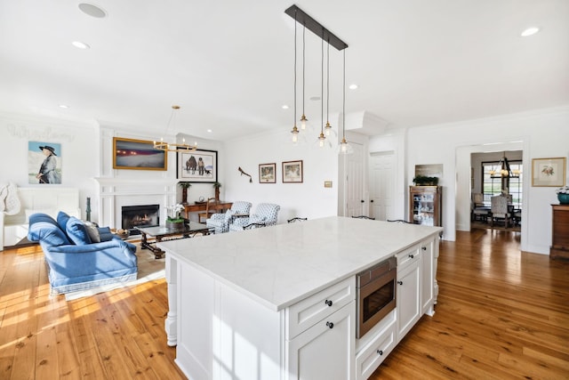 kitchen featuring light wood-style floors, stainless steel microwave, and ornamental molding