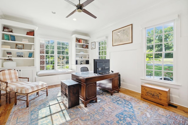 home office featuring ceiling fan, ornamental molding, wood finished floors, and built in features