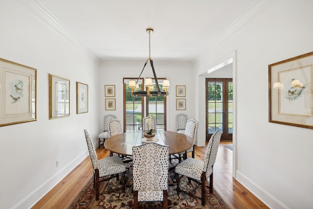 dining space featuring a notable chandelier, ornamental molding, wood finished floors, and baseboards