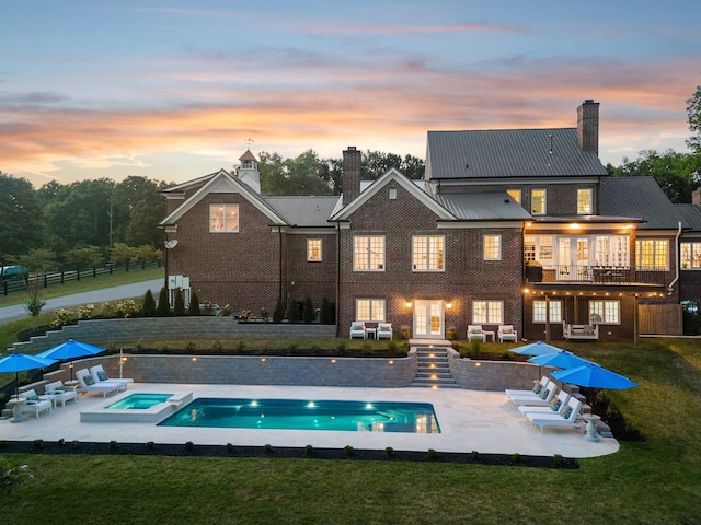 rear view of property with a chimney, a lawn, a patio, and french doors