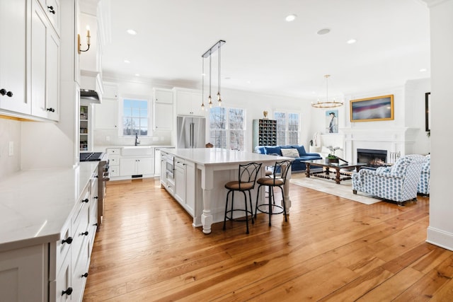 kitchen with open floor plan, light wood finished floors, high end appliances, and a breakfast bar area