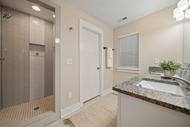 bathroom featuring double vanity, visible vents, a sink, and tiled shower