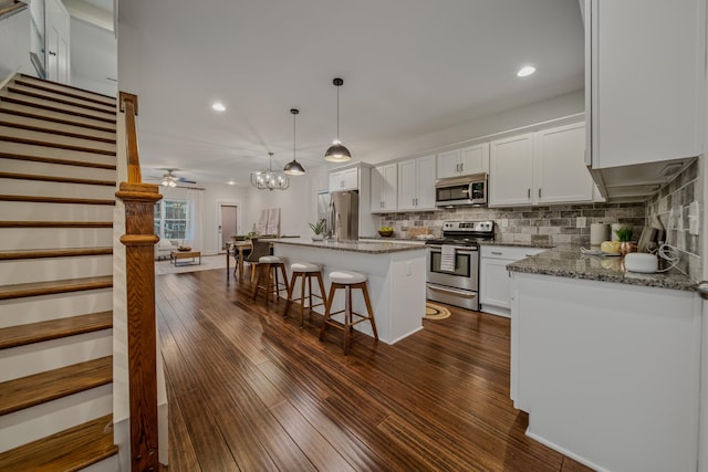 kitchen with stainless steel appliances, a breakfast bar, white cabinetry, dark wood-style floors, and tasteful backsplash