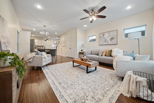 living room with recessed lighting, dark wood-style flooring, baseboards, and ceiling fan with notable chandelier