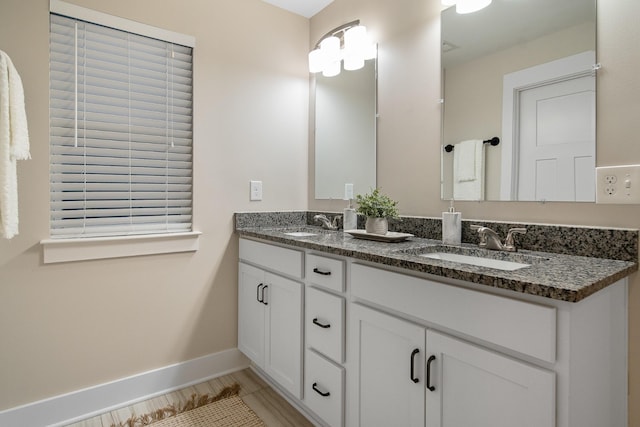 full bathroom featuring a sink, baseboards, and double vanity