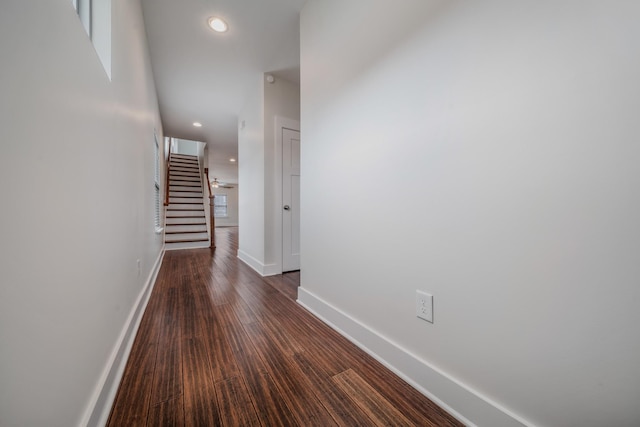 hallway featuring dark wood-style floors, recessed lighting, stairs, and baseboards