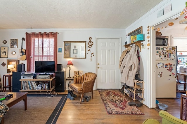 living area with crown molding, wood finished floors, visible vents, and a textured ceiling