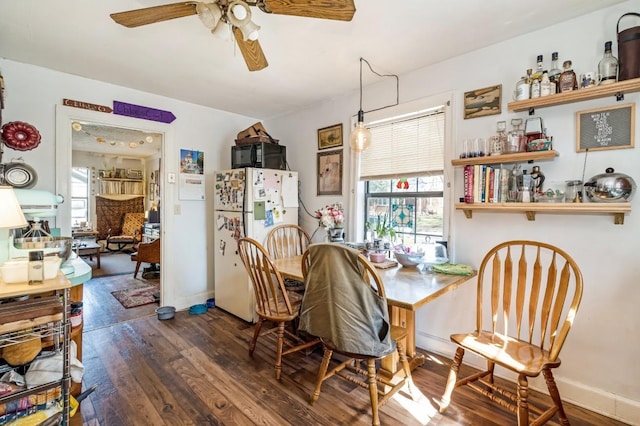 dining room with dark wood finished floors, plenty of natural light, a ceiling fan, and baseboards