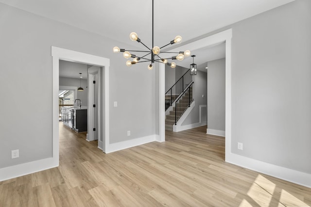 unfurnished dining area with a sink, visible vents, baseboards, light wood-style floors, and stairway