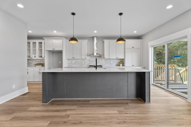 kitchen featuring wall chimney exhaust hood, light countertops, and white cabinetry