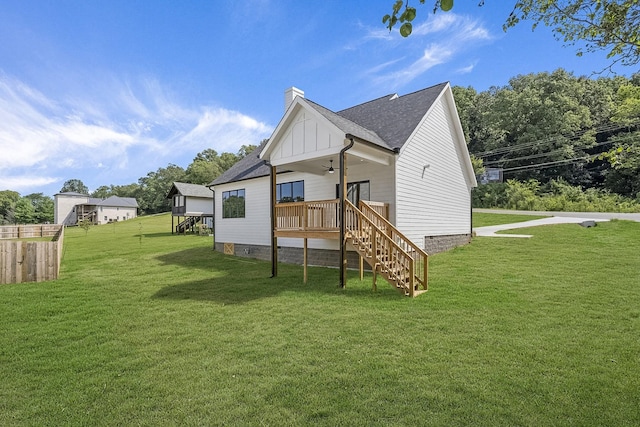 back of house featuring a yard, a chimney, stairway, a ceiling fan, and board and batten siding