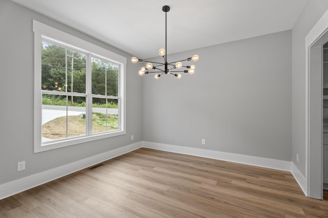 unfurnished room with light wood-type flooring, visible vents, baseboards, and an inviting chandelier