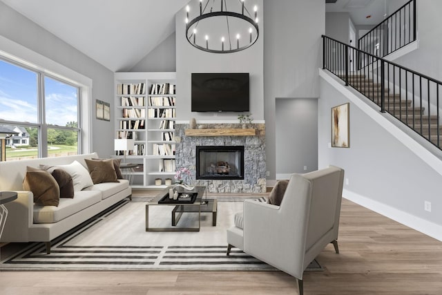 living room with stairway, wood finished floors, a high ceiling, a fireplace, and a chandelier