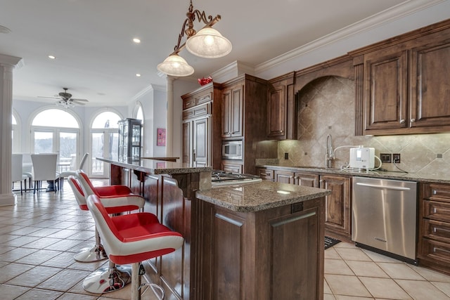 kitchen with built in appliances, a kitchen island, backsplash, and ornate columns