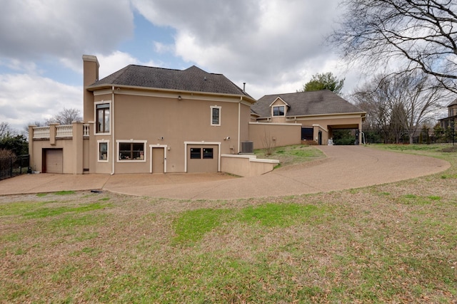 back of house featuring cooling unit, fence, a chimney, and stucco siding