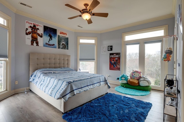 bedroom featuring ornamental molding, visible vents, baseboards, and wood finished floors