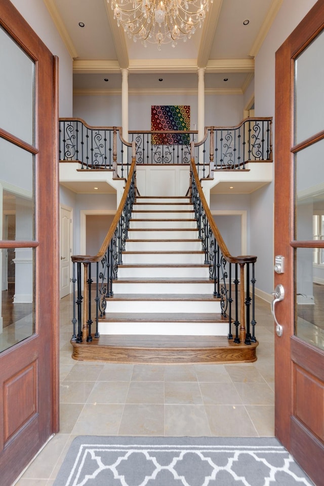 entryway with a towering ceiling, stairs, ornamental molding, and tile patterned floors