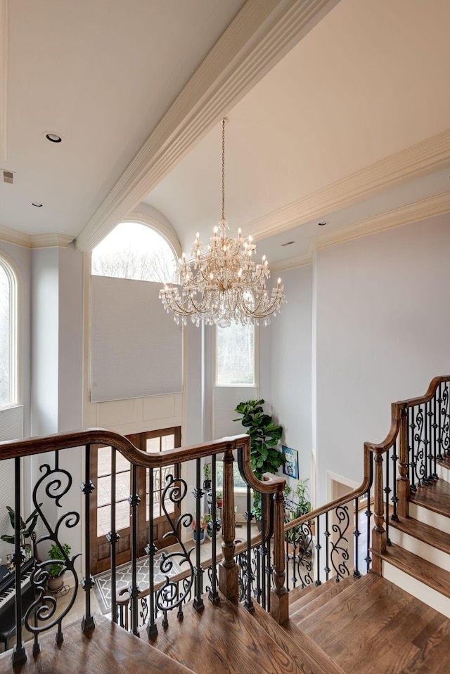 staircase with visible vents, ornamental molding, and wood finished floors