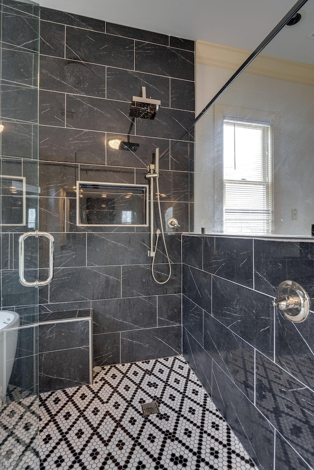 bathroom with ornamental molding and a tile shower