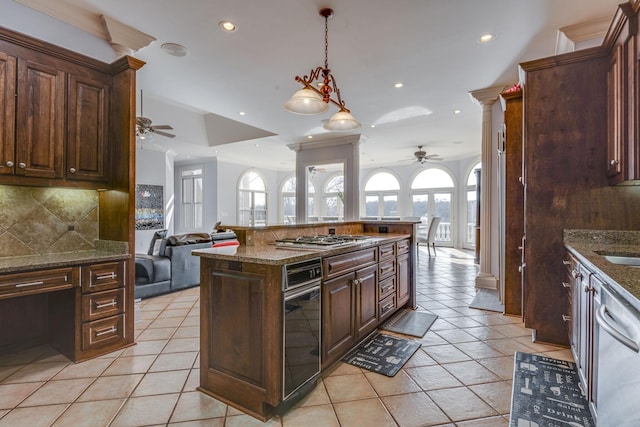 kitchen with light tile patterned floors, decorative backsplash, appliances with stainless steel finishes, open floor plan, and ornate columns