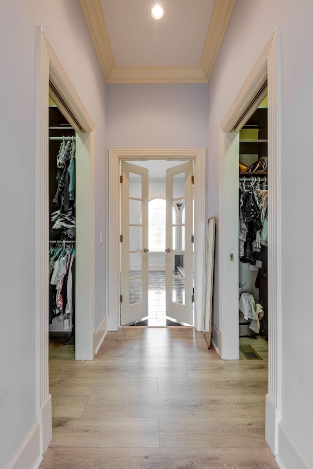 entryway with light wood-style floors, french doors, crown molding, and baseboards