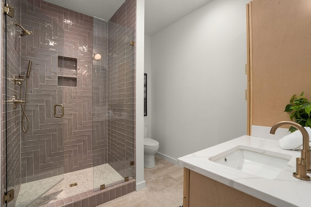 full bathroom featuring a stall shower, vanity, toilet, and baseboards