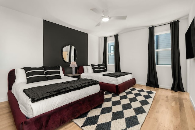 bedroom with light wood-style flooring, baseboards, and ceiling fan