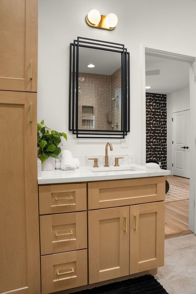 full bath featuring tiled shower and vanity