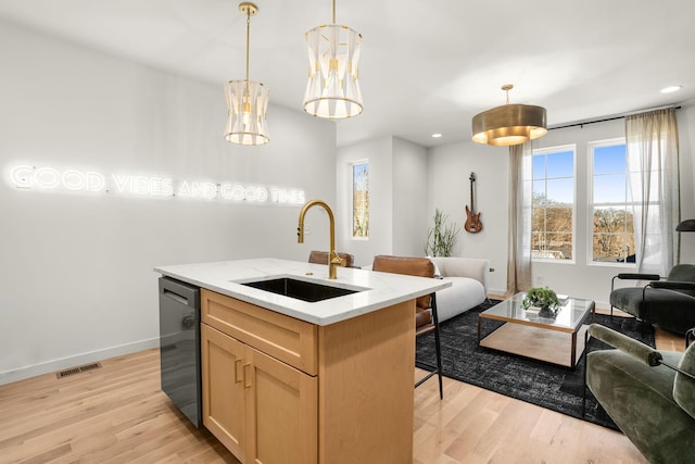 kitchen with light wood-type flooring, dishwashing machine, visible vents, and a sink