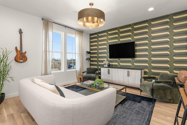 living area with an accent wall, wallpapered walls, baseboards, and wood finished floors