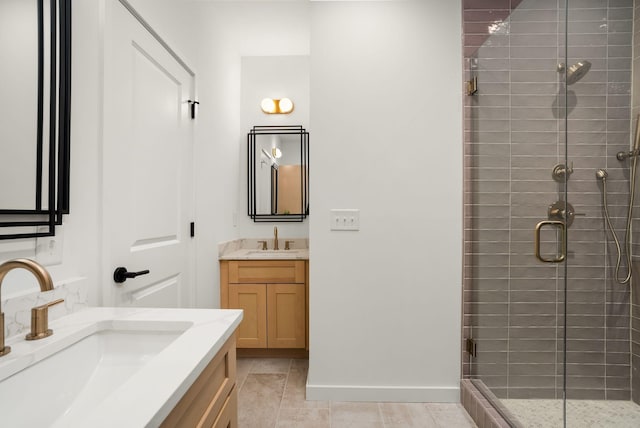 bathroom with a stall shower, baseboards, two vanities, and a sink