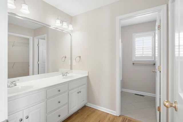 full bathroom with double vanity, baseboards, and a sink