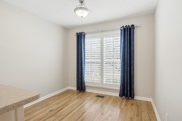 empty room with a healthy amount of sunlight, light wood-style flooring, and baseboards