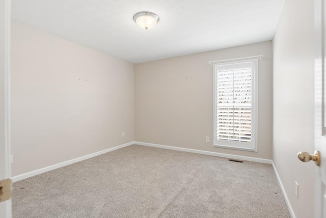 carpeted spare room with visible vents and baseboards