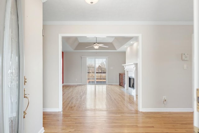 unfurnished living room with light wood-type flooring, a tray ceiling, a ceiling fan, and a premium fireplace