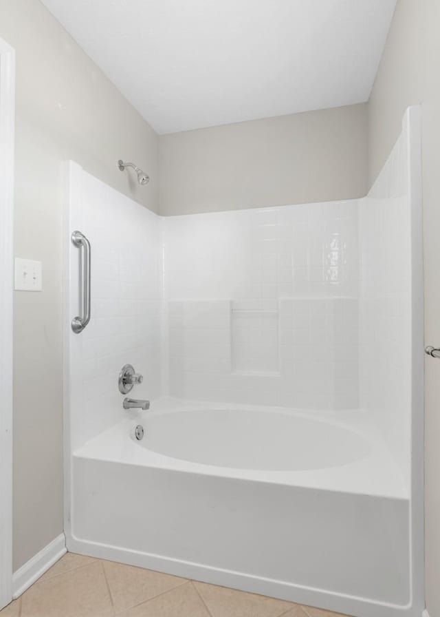 bathroom with washtub / shower combination, tile patterned flooring, and baseboards