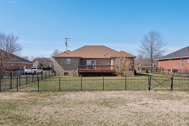 rear view of property featuring a fenced backyard, brick siding, a yard, a wooden deck, and a gate