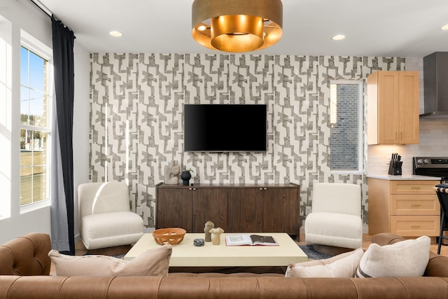 living room featuring wallpapered walls, an accent wall, and recessed lighting