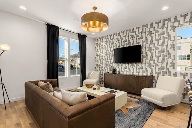 living area with wallpapered walls, an accent wall, and light wood finished floors