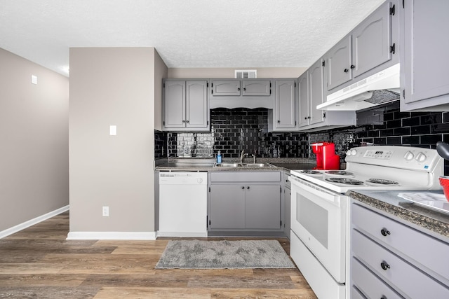 kitchen featuring under cabinet range hood, white appliances, a sink, visible vents, and gray cabinets