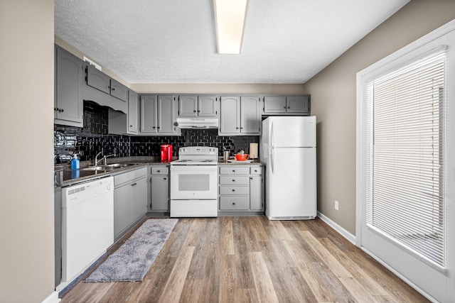 kitchen with white appliances, plenty of natural light, under cabinet range hood, and gray cabinetry