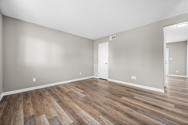 spare room with baseboards, a textured ceiling, visible vents, and wood finished floors