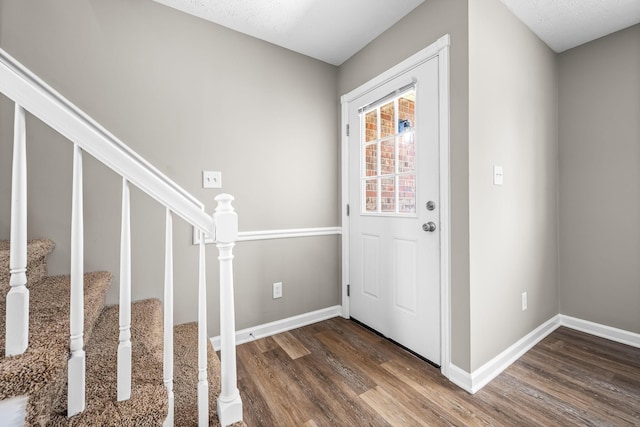 foyer entrance with stairs, wood finished floors, and baseboards