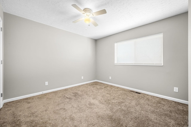 carpeted spare room with baseboards, ceiling fan, visible vents, and a textured ceiling