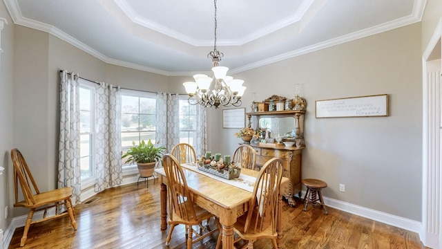 dining area with a notable chandelier, wood finished floors, visible vents, baseboards, and a tray ceiling