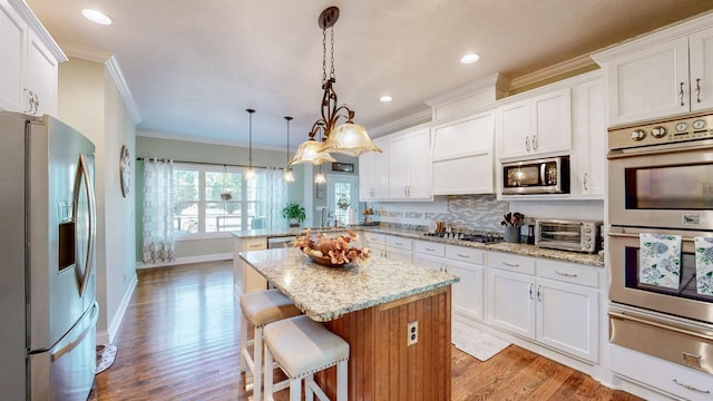 kitchen featuring tasteful backsplash, ornamental molding, a peninsula, stainless steel appliances, and a warming drawer