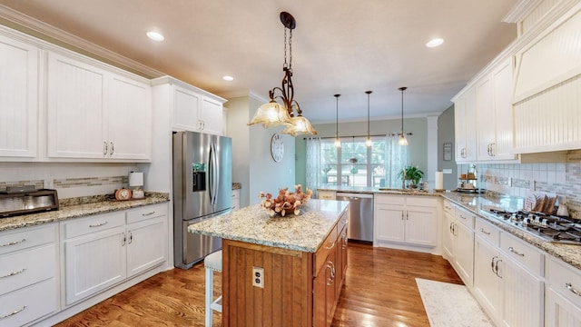 kitchen featuring stainless steel appliances, wood finished floors, white cabinetry, and crown molding