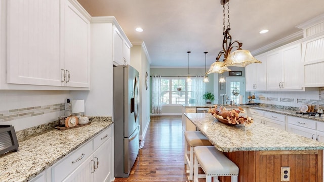 kitchen featuring white cabinets, stainless steel fridge, crown molding, and backsplash